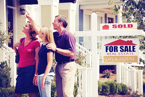 Family looking at house by "sold" sign